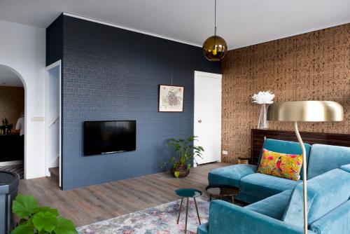 a living room with a blue couch and a tv at Rooftop 52, City-Apartment in Assen