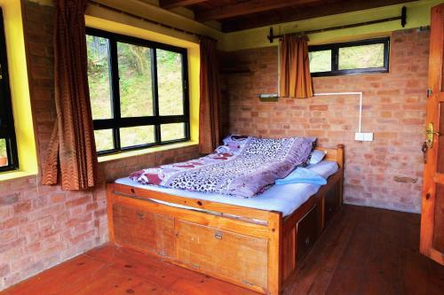 a bed in a room with a brick wall at Hotel At The End Of The Universe in Nagarkot