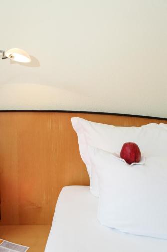 a red apple sitting on top of a bed at Ringhotel VITALHOTEL ambiente in Bad Wilsnack