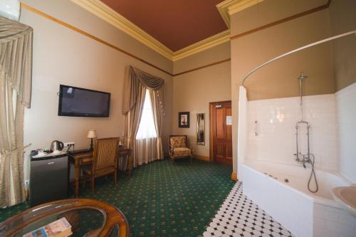 a room with a bathroom with a tub and a table at Denison Boutique Hotel in Rockhampton