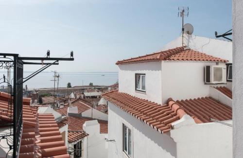 a view of roofs of buildings and the ocean at Cosy Alfama in Lisbon