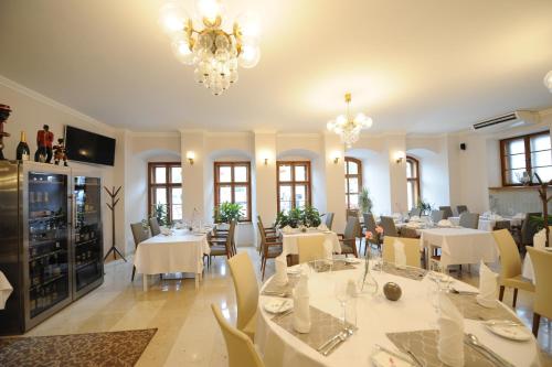 un restaurante con mesas y sillas blancas y una lámpara de araña en Hotel Prince de Ligne, en Teplice