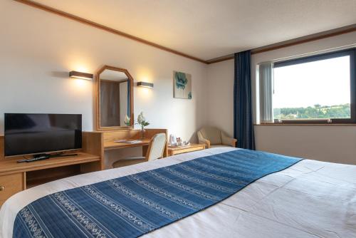 a hotel room with a large bed and a television at Passage House Hotel in Newton Abbot