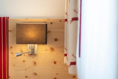 a light on a wall next to a bed at Bergsporthotel Antonie in Gries im Sellrain