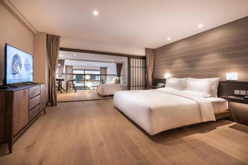 a bedroom with a large white bed and a flat screen tv at Novotel Suites Shanghai Hongqiao in Shanghai