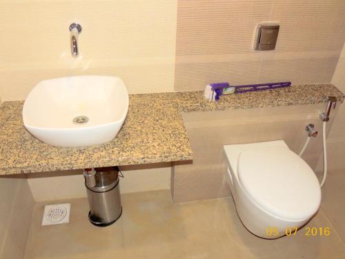 a bathroom with a sink and a toilet at Hotel Darshan in Visnagar