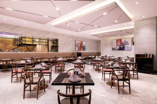 上海市にあるNovotel Suites Shanghai Hongqiaoのテーブルと椅子が備わるレストラン