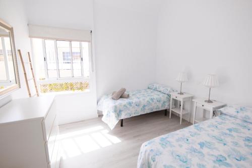 サンアグスティンにあるDeluxe Apartment. 50 meters Beachの白い部屋で、ベッド2台、窓が備わります。