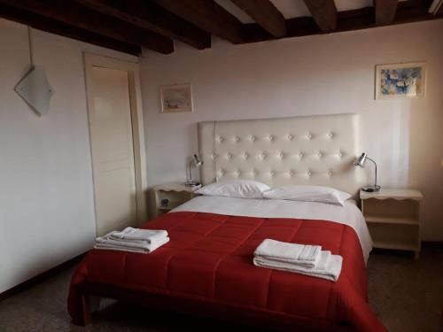 a bedroom with a red and white bed with towels on it at Cà Del Giazzo in Venice