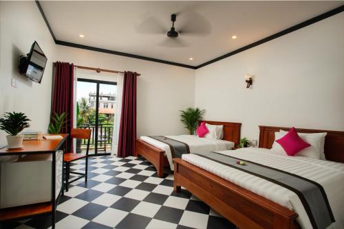een slaapkamer met 2 bedden en een dambordvloer bij Noni Tree Hostel in Siem Reap