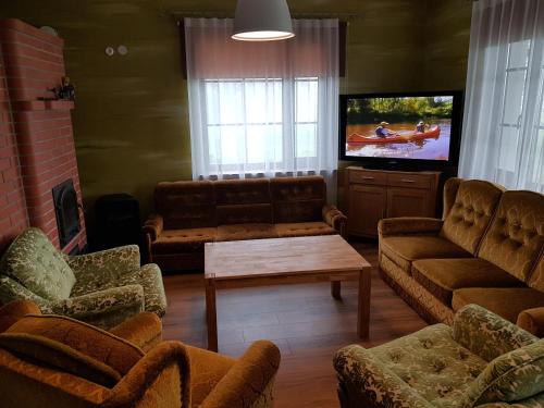 ein Wohnzimmer mit Sofas und einem Flachbild-TV in der Unterkunft Soomaa Canoe Trips Centre in Tohera