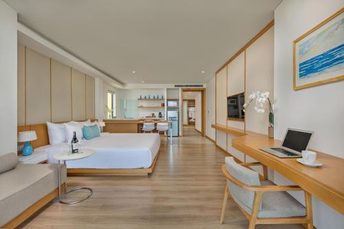 a hotel room with a bed and a desk with a laptop at TMS Hotel Da Nang Beach in Da Nang