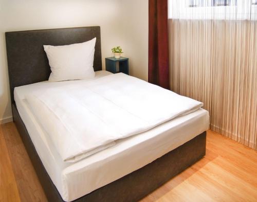 カールスルーエにあるSEEGER Living Premium Westの白いシーツと黒いヘッドボードが備わるベッド