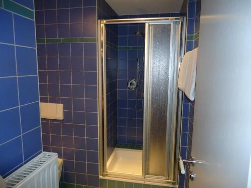 y baño con ducha de azulejos azules. en Garni Hotel Kaiserdom, en Bamberg