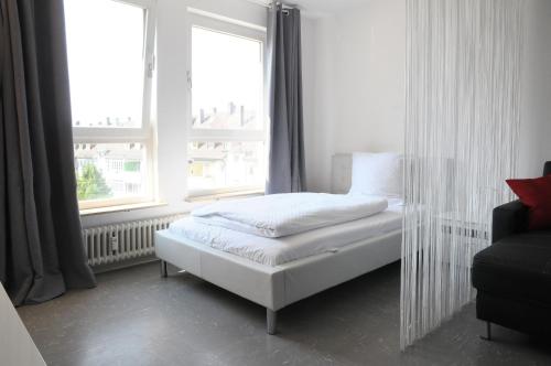 a white bed in a room with two windows at SEEGER Living Classic East in Karlsruhe