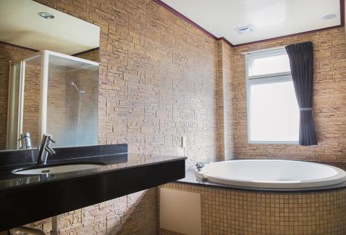 a bathroom with a tub and a sink and a window at 意大利溫泉會館 in Jiaoxi