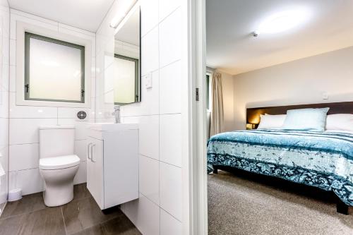 Baño blanco con cama y aseo en Hunters Moon, en Mosgiel