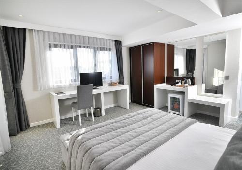 Dormitorio con cama, escritorio y TV en Güvenay Business Hotel en Ankara