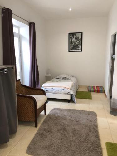 - une chambre avec un lit, une chaise et un tapis dans l'établissement Les Chambres de Carreau, à Meilhan-sur-Garonne