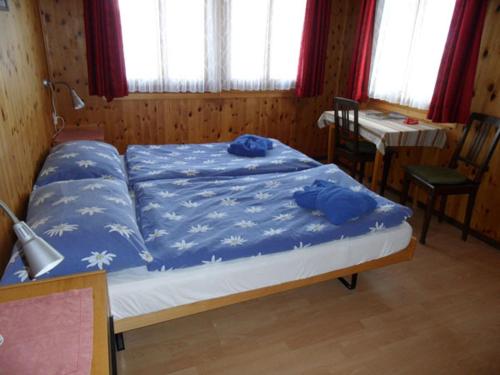 a bedroom with a large bed with blue sheets at Hotel Restaurant Emshorn in Oberems