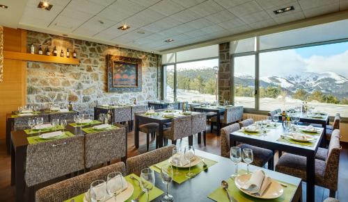 a restaurant with tables and chairs with mountains in the background at Hotel & Spa La Collada in Toses