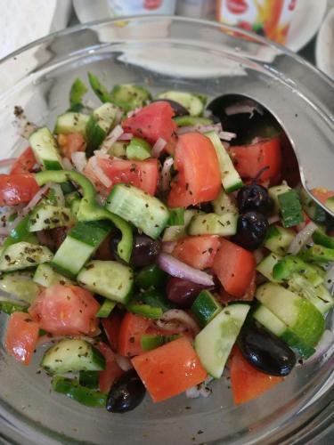 a salad with vegetables in a bowl with a spoon at Hotel @Syngrou Fix in Athens
