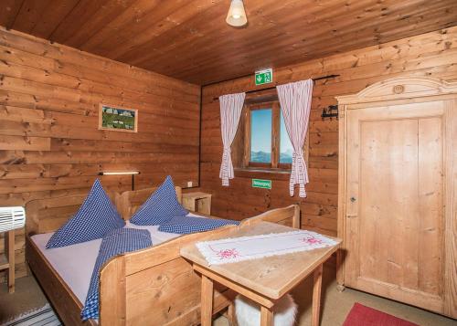 a log cabin with a bed and a table at Hocheckhuette On Top of the Kitzbuehel Hahnenkamm Mountain in Kitzbühel
