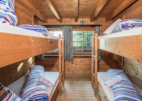 a room with three bunk beds in a log cabin at Hocheckhuette On Top of the Kitzbuehel Hahnenkamm Mountain in Kitzbühel