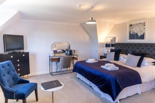 a bedroom with a bed and a tv and a chair at Cricket Field House in Salisbury
