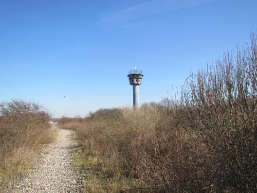 a lighthouse on top of a hill with a dirt road at Haus Calmsailing in Börgerende-Rethwisch