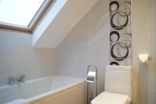 a bathroom with a tub and a toilet and a window at Modern, Cosy Apartment In Bearsden with Private Parking in Glasgow