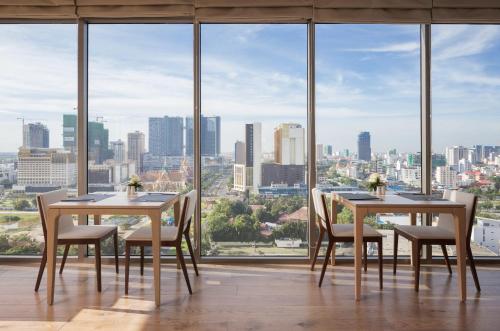 a dining room with two tables and chairs and a large window at Hotel Emion Phnom Penh in Phnom Penh