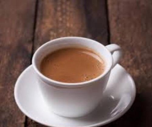 a cup of coffee sitting on a plate on a table at Ahlan Green Apple Dormitory in Mumbai