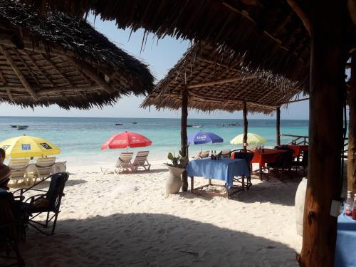 un grupo de mesas y sombrillas en una playa en Ebony & Ivory Beach Bungalows, en Nungwi