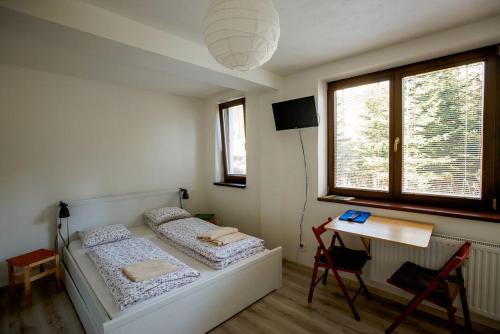a bedroom with two beds and a table and a desk at Apartments Pod Kotlom in Vysoke Tatry - Horny Smokovec
