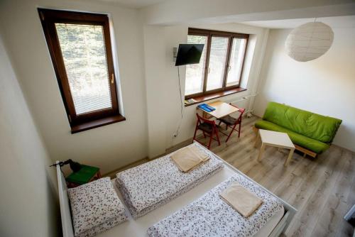 a room with two beds and a green couch at Apartments Pod Kotlom in Vysoké Tatry