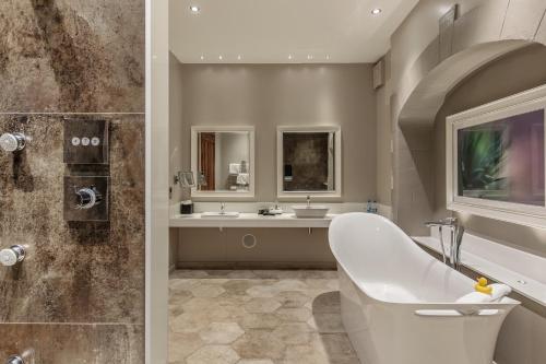 een badkamer met een bad, een douche en een wastafel bij Lainston House in Winchester