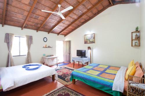 a bedroom with two beds and a ceiling fan at The Blue Mountains Estate Stay in Madikeri