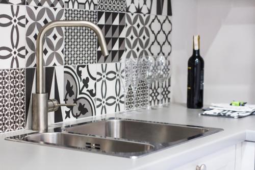 a stainless steel sink in a kitchen with black and white tiles at My Old Town Gdańsk - Apartamenty Długa 56 in Gdańsk