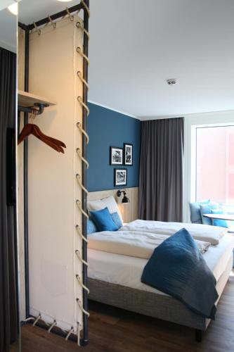 a bedroom with a large bed with blue walls at HARBR. hotel Konstanz in Konstanz