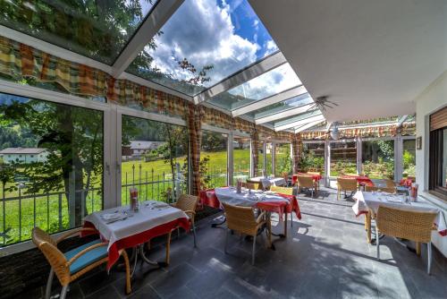a restaurant with tables and chairs and large windows at Hotel Schwarzbachhof in Lutago