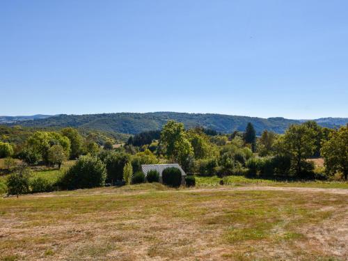 um campo aberto com um celeiro à distância em Comfy holiday home with private garden em Neuvéglise
