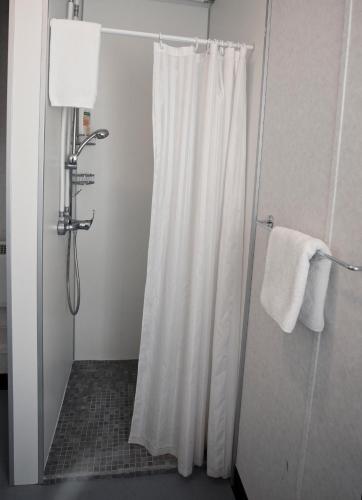 a shower with a white shower curtain in a bathroom at Hestaland Guesthouse Horse Farm Stay in Staðarhús