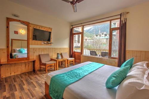 a bedroom with a large bed and a large window at Hotel Mountain face by Snow City Hotels in Manāli