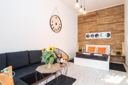 un soggiorno con divano nero e orologio sul muro di Cracow Best Location Apartment with Garden by Cozyplace a Cracovia