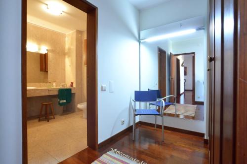 a room with a blue chair and a bathroom at sunset@leçadapalmeira in Matosinhos