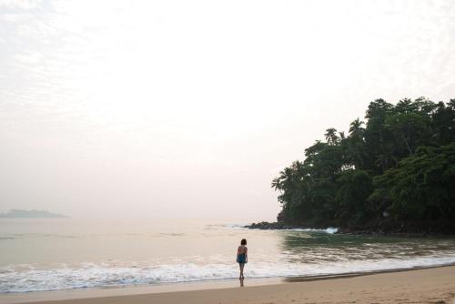 a person standing on a beach near the ocean at Talalla Retreat in Talalla