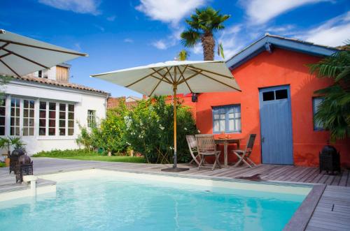 a house with a swimming pool and an umbrella at La Ferrade Chambres d'Hôtes B&B in Bègles
