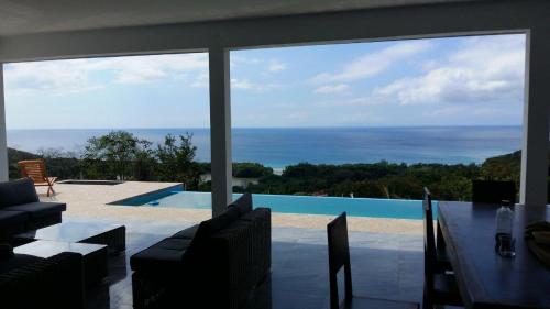 a dining room with a view of a swimming pool at Savane Paille in Deshaies
