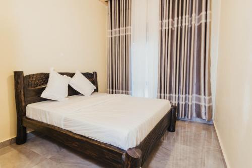 a bedroom with a bed with white sheets and a window at Mountain View Hotel & Apartment in Kigali